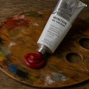 Winsor & Newton Winton Oil Paint Cadmium Deep Red Hue 200ml tube shown on a stained wooden artist's palette with a rich red paint dollop.